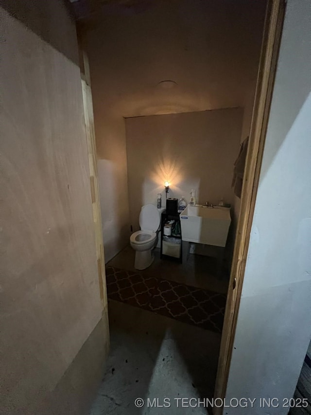 bathroom with a sink, concrete flooring, and toilet