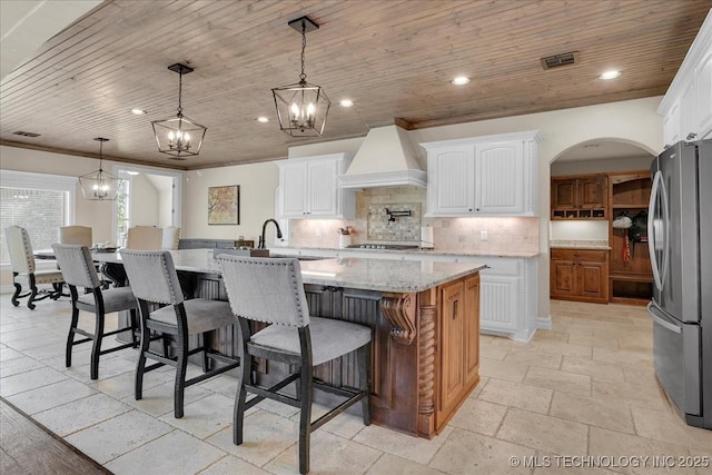kitchen featuring stainless steel appliances, a notable chandelier, a sink, and premium range hood