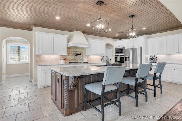 kitchen featuring a sink, arched walkways, custom exhaust hood, and stainless steel appliances