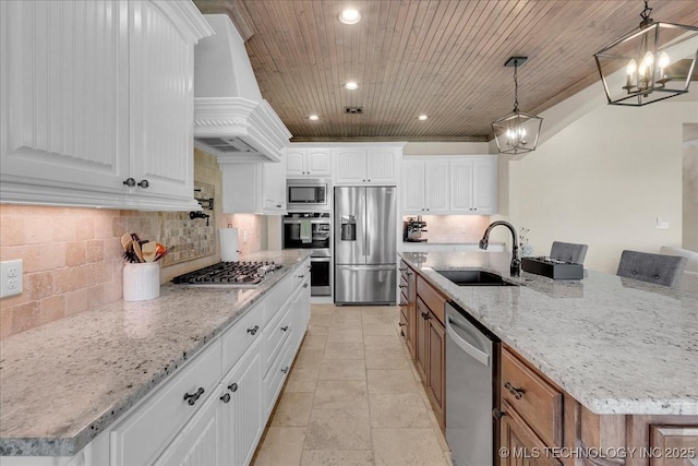 kitchen with tasteful backsplash, a sink, premium range hood, an inviting chandelier, and stainless steel appliances