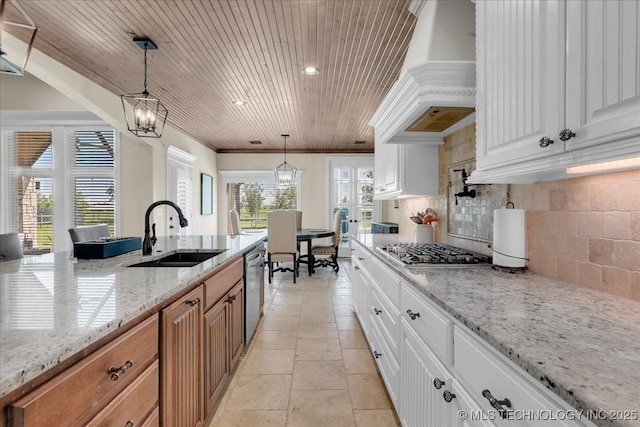 kitchen featuring a sink, stainless steel appliances, custom range hood, and light stone counters