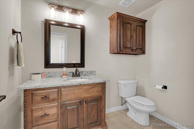 half bath with visible vents, baseboards, tile patterned floors, vanity, and toilet