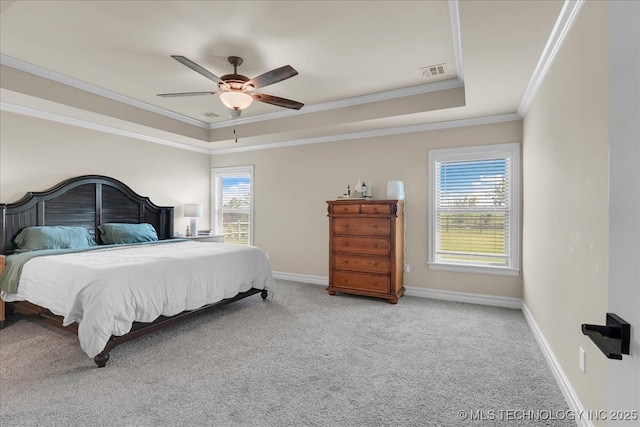 carpeted bedroom with visible vents, ornamental molding, baseboards, a tray ceiling, and a ceiling fan