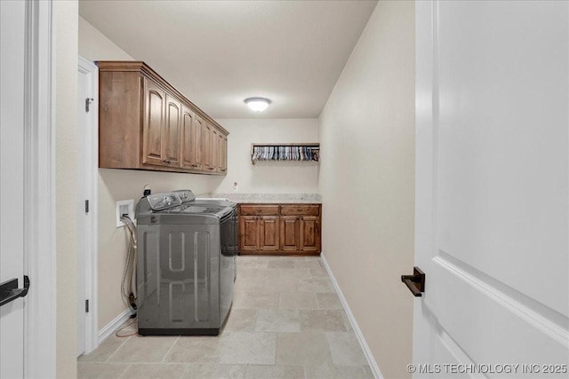 laundry room featuring baseboards, stone finish floor, cabinet space, and washer and dryer