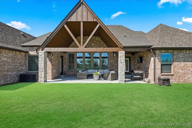 rear view of house featuring roof with shingles, brick siding, outdoor lounge area, a patio area, and a yard
