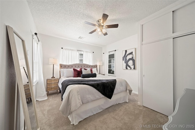carpeted bedroom with a ceiling fan, a textured ceiling, and visible vents