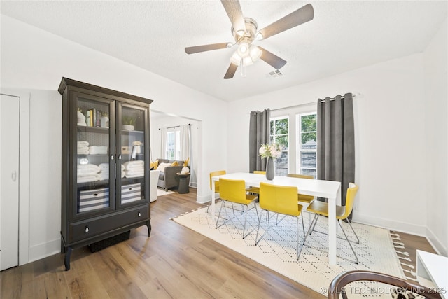 dining area with a ceiling fan, visible vents, a healthy amount of sunlight, and wood finished floors