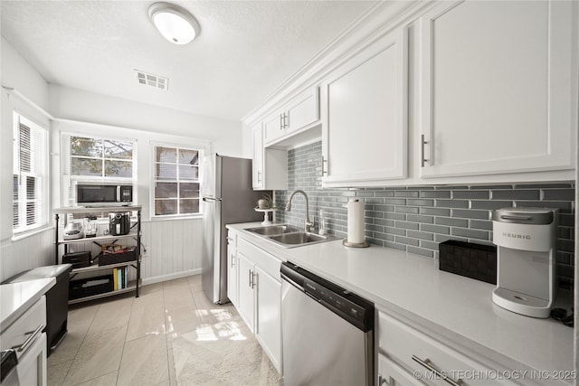 kitchen with visible vents, light countertops, white cabinetry, a sink, and stainless steel appliances