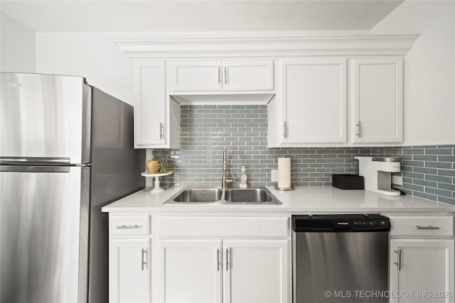 kitchen with appliances with stainless steel finishes, tasteful backsplash, a sink, light countertops, and white cabinets