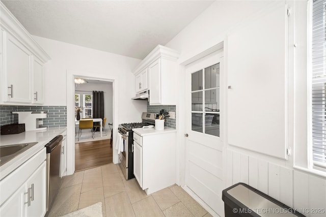 kitchen featuring decorative backsplash, light countertops, under cabinet range hood, white cabinets, and stainless steel appliances