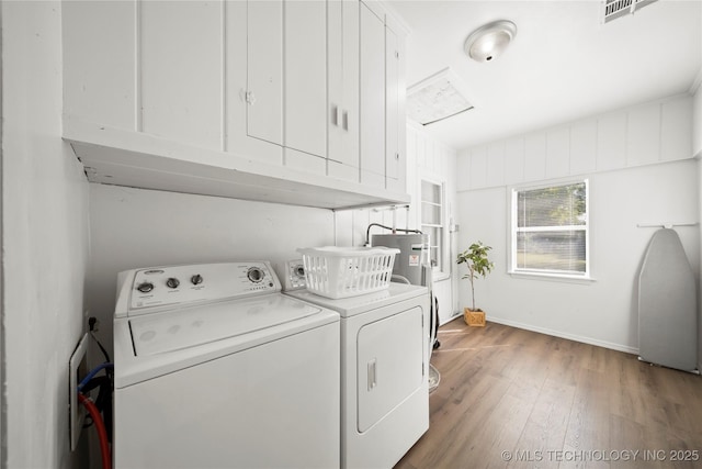 laundry room featuring cabinet space, baseboards, wood finished floors, washer and clothes dryer, and electric water heater
