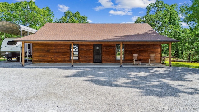 view of front facade with roof with shingles and a detached carport
