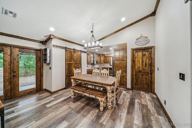 dining room with baseboards, ornamental molding, a barn door, and visible vents