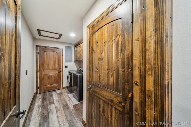 washroom featuring wood finished floors, attic access, cabinet space, and washer and clothes dryer