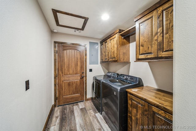 laundry area with electric panel, washing machine and clothes dryer, wood finished floors, cabinet space, and baseboards