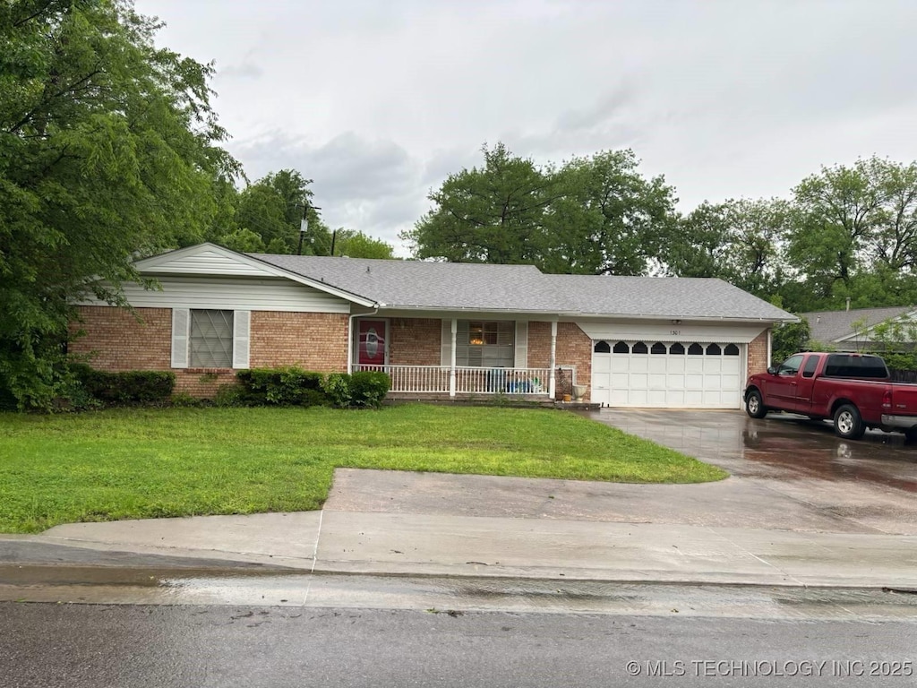 single story home featuring brick siding, a front lawn, an attached garage, and a porch