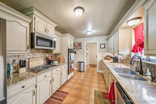 kitchen with backsplash, baseboards, appliances with stainless steel finishes, and a sink