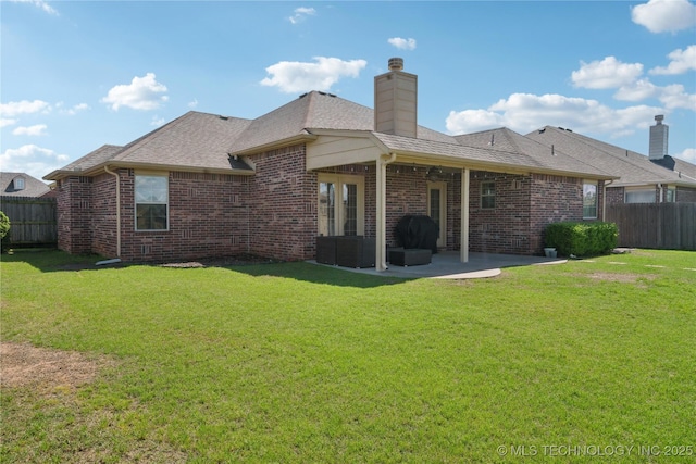 back of house featuring brick siding, a patio area, fence, and a yard