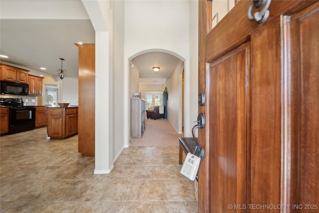 foyer featuring arched walkways, baseboards, and recessed lighting