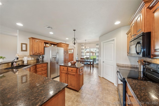 kitchen featuring visible vents, arched walkways, tasteful backsplash, a sink, and black appliances