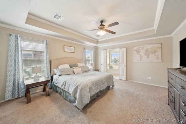 bedroom with a tray ceiling, visible vents, multiple windows, and ornamental molding