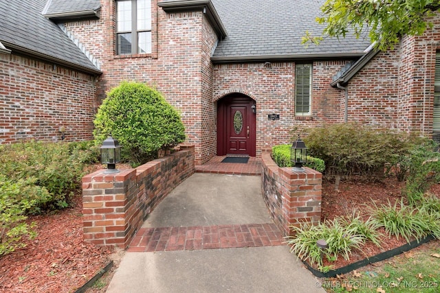 doorway to property featuring brick siding and a high end roof