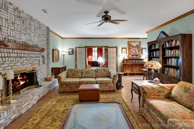 living area with crown molding, ceiling fan, a brick fireplace, and wood finished floors