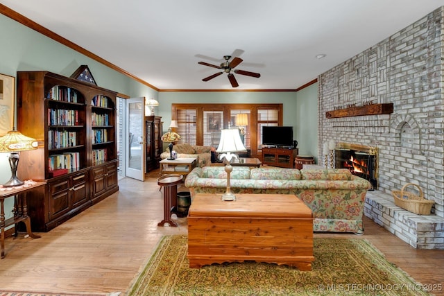 living area featuring ornamental molding, light wood finished floors, ceiling fan, and a fireplace