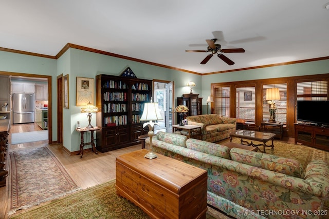 living area featuring baseboards, ornamental molding, light wood-style flooring, and ceiling fan