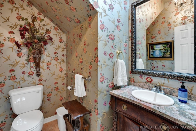 bathroom with toilet, wallpapered walls, tile patterned floors, and vanity