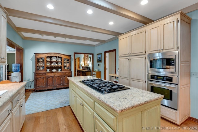 kitchen featuring a kitchen island, appliances with stainless steel finishes, light wood-type flooring, beam ceiling, and light stone counters