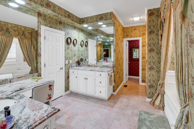 bathroom featuring crown molding, baseboards, wallpapered walls, two vanities, and a sink