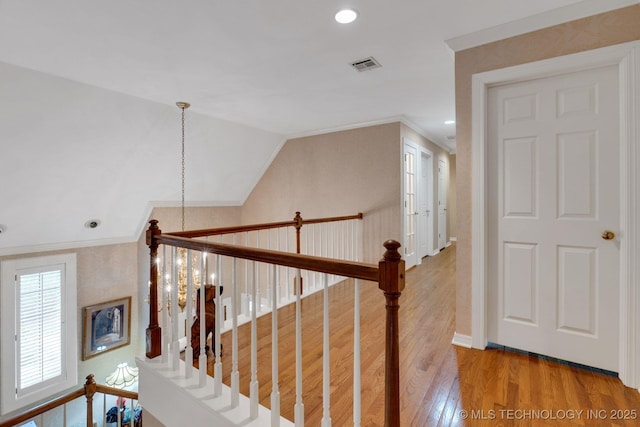 hall featuring crown molding, visible vents, an upstairs landing, and hardwood / wood-style floors