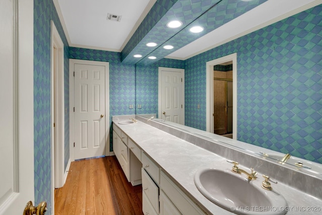 bathroom featuring crown molding, visible vents, double vanity, wood finished floors, and a sink