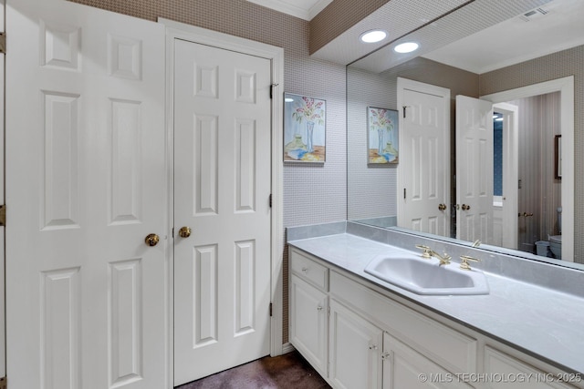 bathroom with crown molding, vanity, wallpapered walls, and toilet