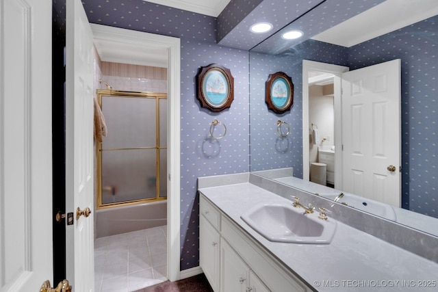 bathroom featuring tile patterned flooring, vanity, bath / shower combo with glass door, toilet, and wallpapered walls