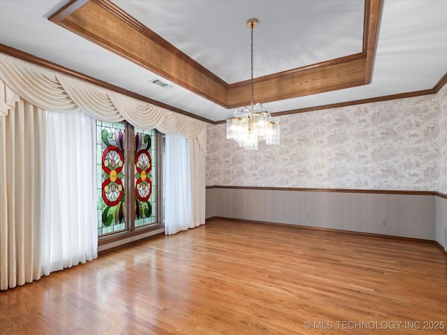 unfurnished dining area featuring visible vents, wainscoting, a notable chandelier, and wallpapered walls