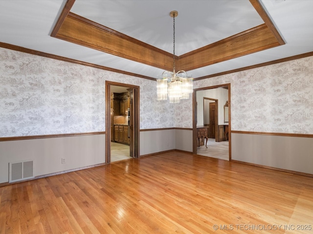 unfurnished dining area with visible vents, a wainscoted wall, a notable chandelier, and wallpapered walls
