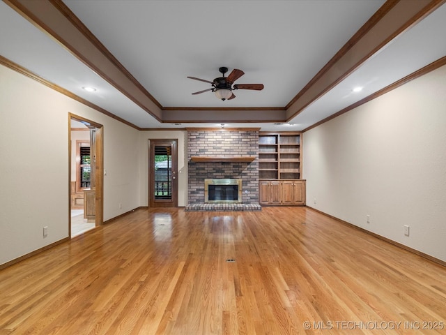 unfurnished living room with crown molding, light wood-style flooring, a raised ceiling, and a brick fireplace
