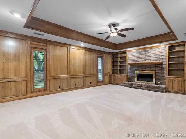 unfurnished living room with crown molding, ceiling fan, a tray ceiling, and carpet flooring