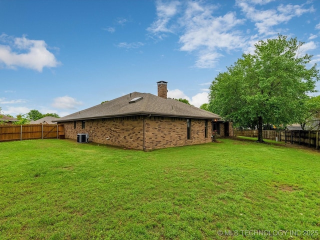 rear view of property with a lawn, a fenced backyard, and brick siding