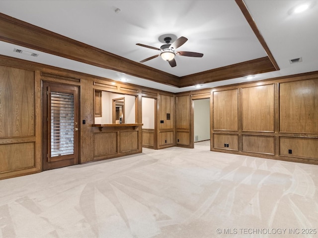 unfurnished bedroom featuring crown molding, visible vents, light carpet, and a decorative wall