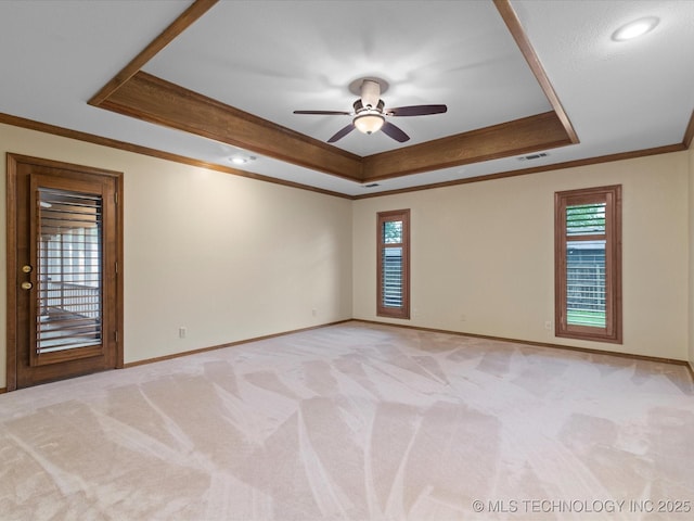empty room featuring visible vents, ornamental molding, a raised ceiling, and baseboards