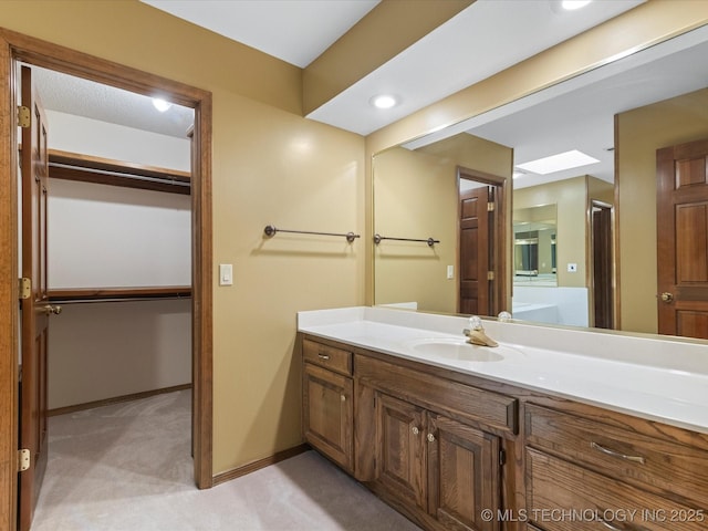 bathroom featuring vanity, baseboards, and a spacious closet