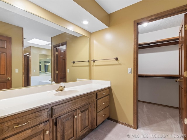 bathroom featuring vanity, baseboards, and a spacious closet