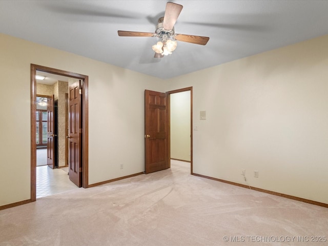 spare room with baseboards, ceiling fan, and light carpet