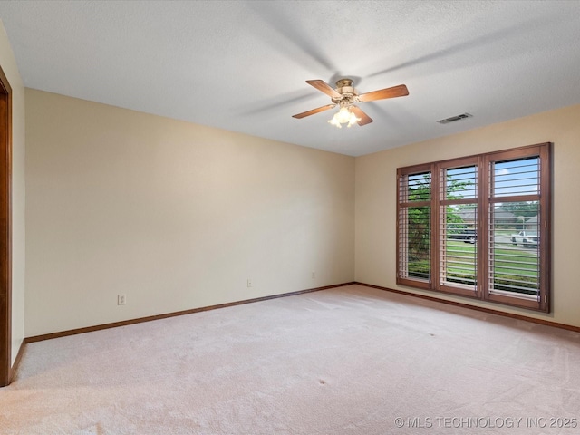 unfurnished room with baseboards, a ceiling fan, light colored carpet, and visible vents