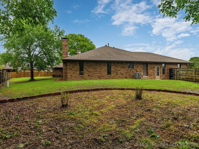 rear view of house featuring brick siding, a fenced backyard, a chimney, and cooling unit