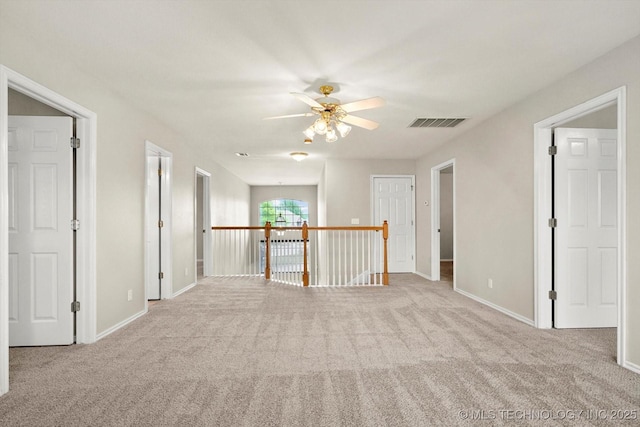 carpeted empty room featuring visible vents, baseboards, and ceiling fan
