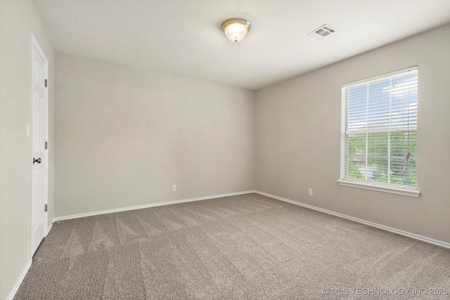 spare room with carpet flooring, baseboards, and visible vents